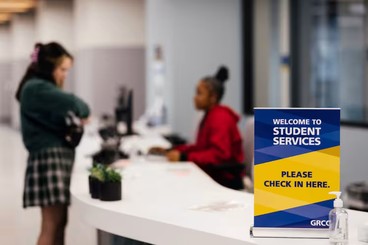 Students at a check-in desk inside GRCC's Student Services center.