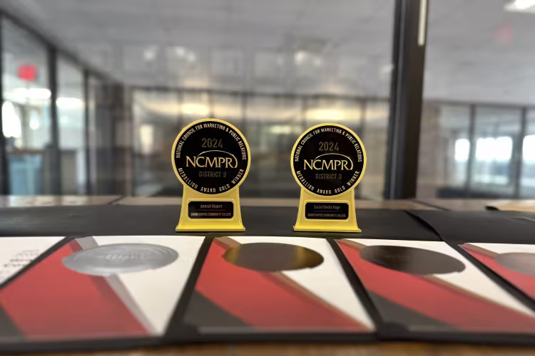 Seven awards placed on a table, representing the recognition GRCC's Marketing and Communications team received from the National Council for Marketing and Public Relations.