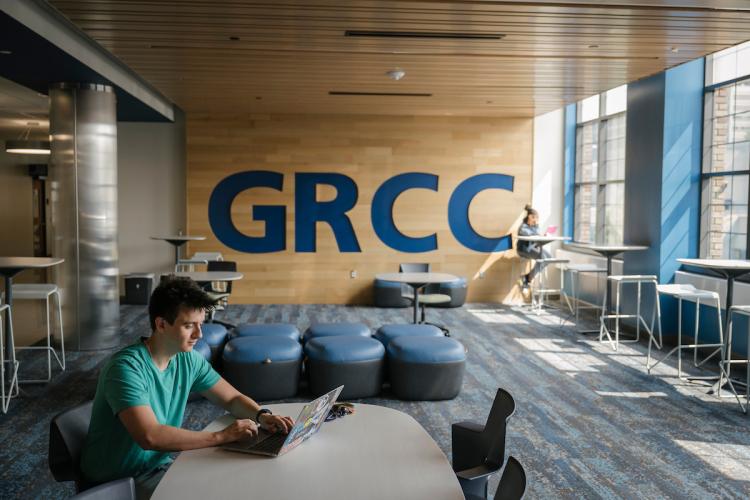 A male student works on a laptop in a GRCC student lounge space.