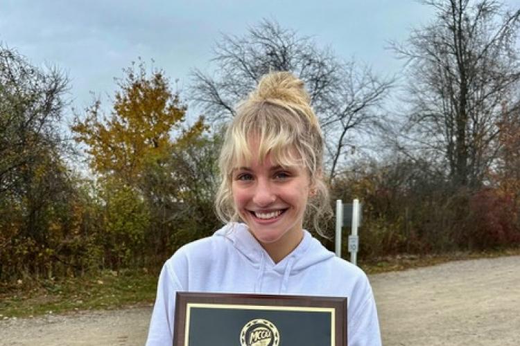 GRCC athlete Mariana Zaragoza holds here cross country champions plaque.