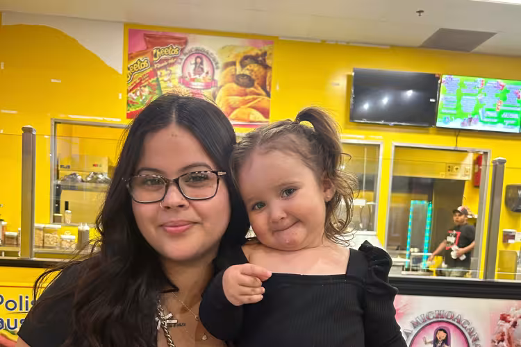 GRCC student Leah Santiago holds her young daughter, Xylia, in her arms for a photo.