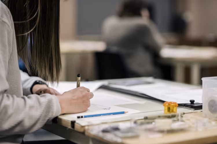 A person drafts an interior design using pen and pencil.