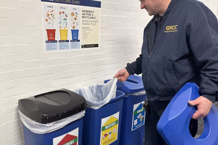 A person removes a bag in a recycling bin.