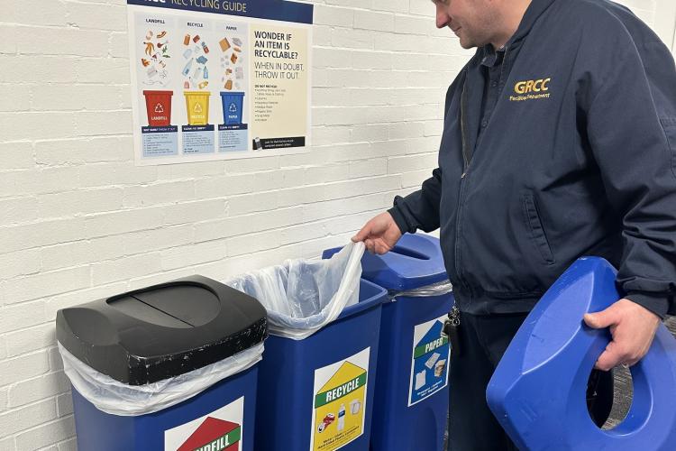 A person removes a bag in a recycling bin.