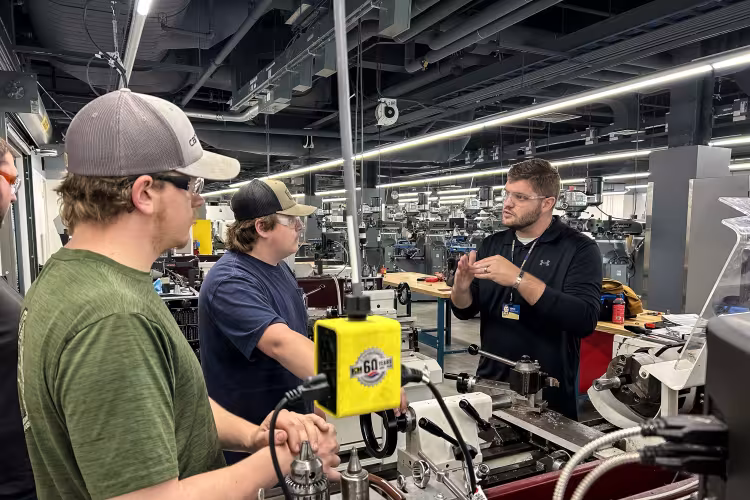 Jake Nichols speaks with two students in a machine lab.