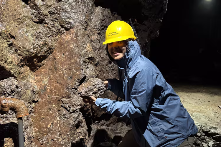 Yasmina Zimmer poses wearing a hardhat near a rock formation.