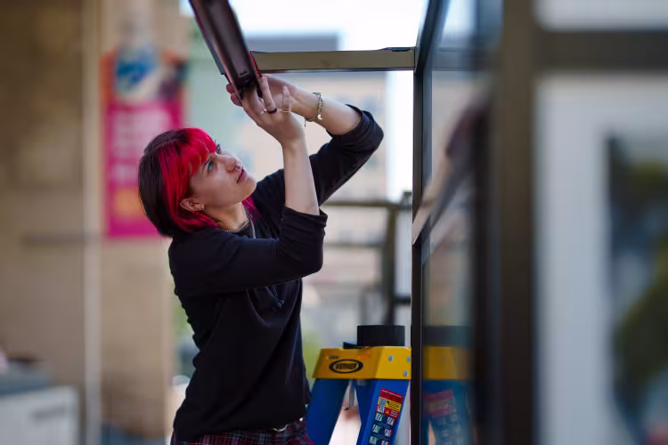 A person concentrates, working with a metal beam