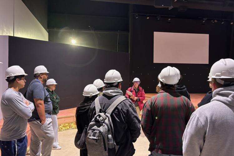 A group of students listen to an architect during a construction site tour.