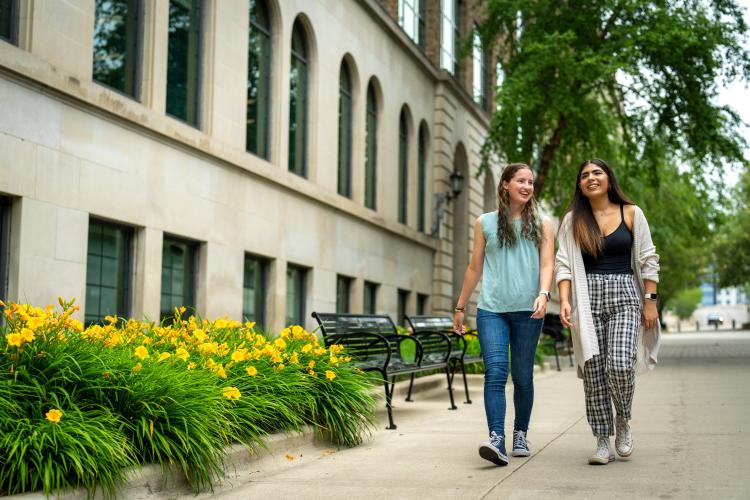 Two guest students walk side by side on GRCC's main campus.