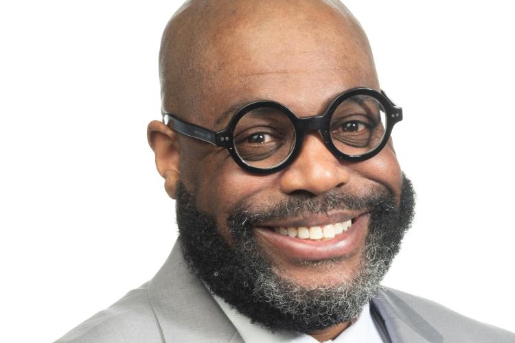 Maurice Baker in a gray suit and glasses.