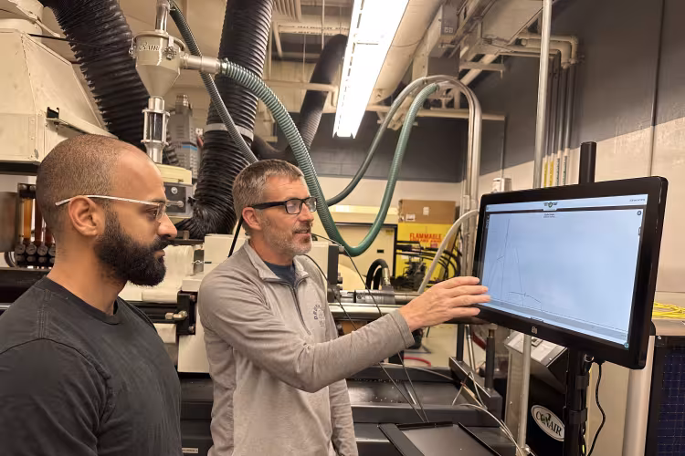 Assistant professor Scott Van Hoven shows a student how to use new monitoring technology in the plastics lab.