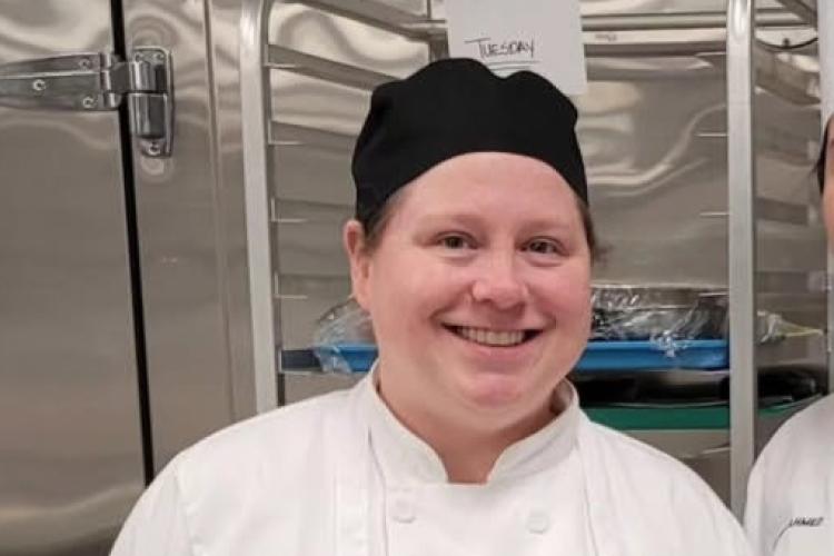 Quinn Thomas in a white chef coat and apron.