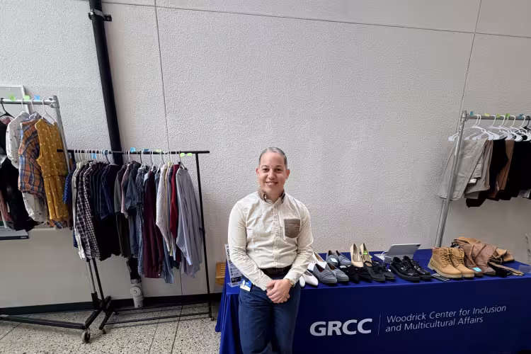 Joel Reyes Hernandez stands beside the student clothing pop-up.