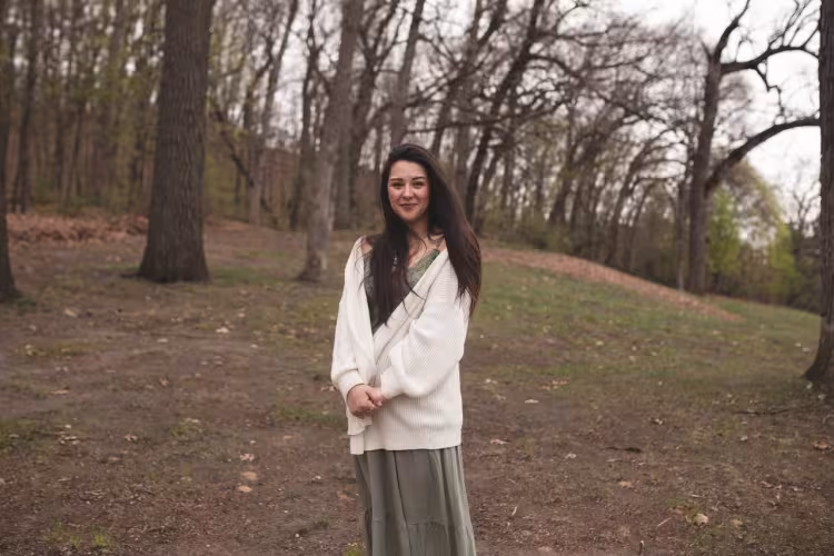Toni Keniston stands outside in a wooded area.