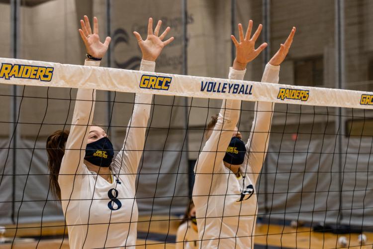 Volleyball players leaping to block a shot.