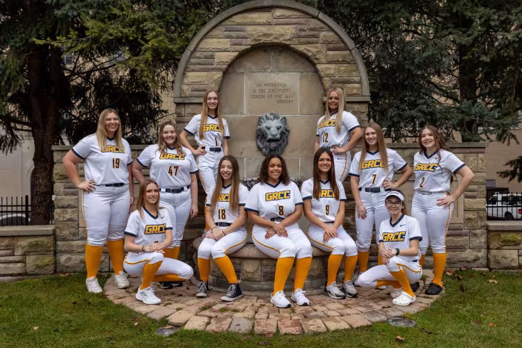 GRCC softball players posting bythe iconic lion fountain.