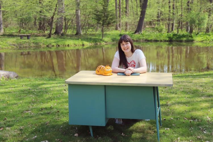 Abby Haywood sitting at a desk near a pond. 
