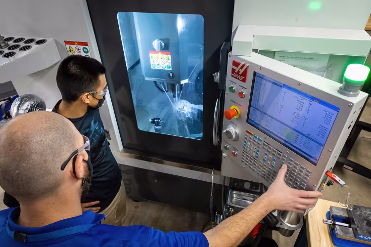Students and professor working on a CNC machine.