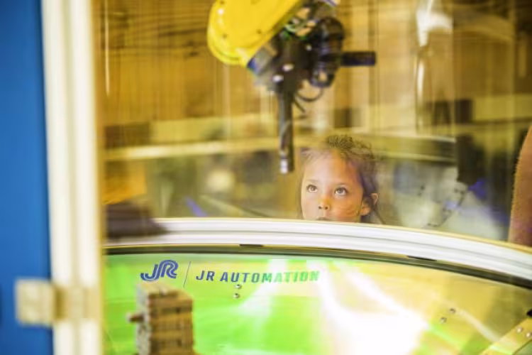 Future engineer watching a robotic arm in action.