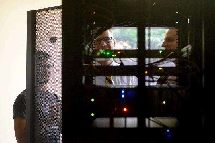 GRCC students and professor looking at a computer server, viewed from the back.