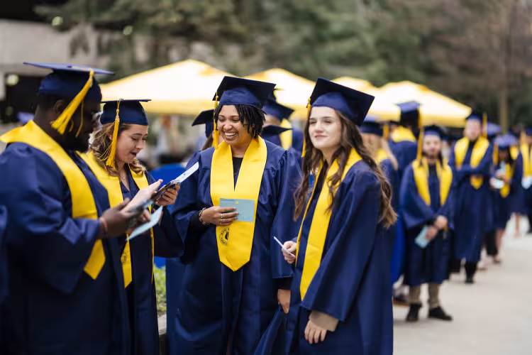 Graduates in GRCC caps and gowns converse outside.