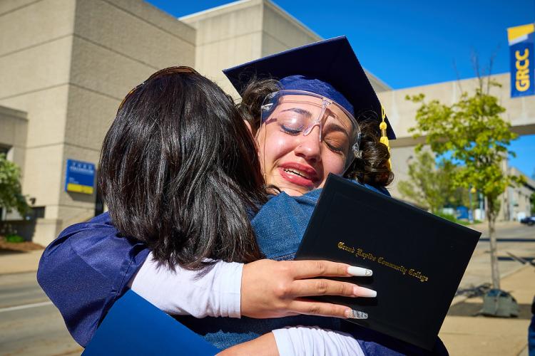 A student graduating in 2021 hugs a family member.