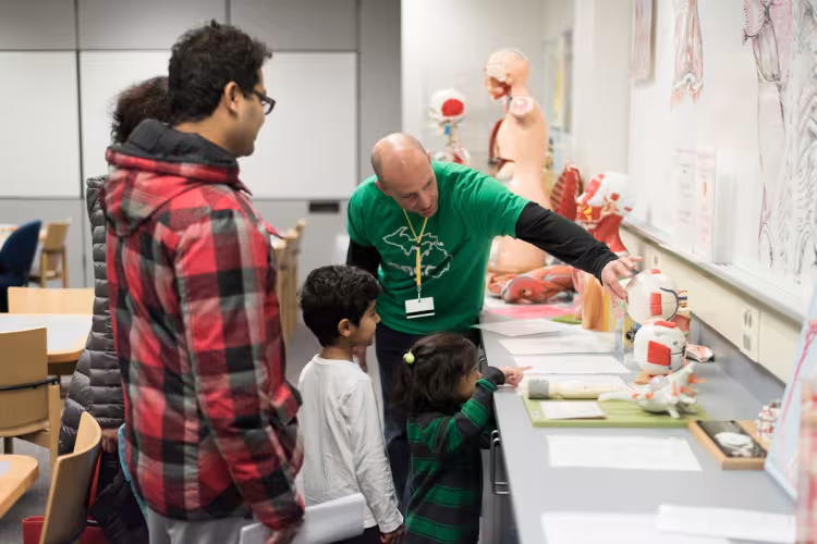 A man points to a model of an eyeball while talking to children.