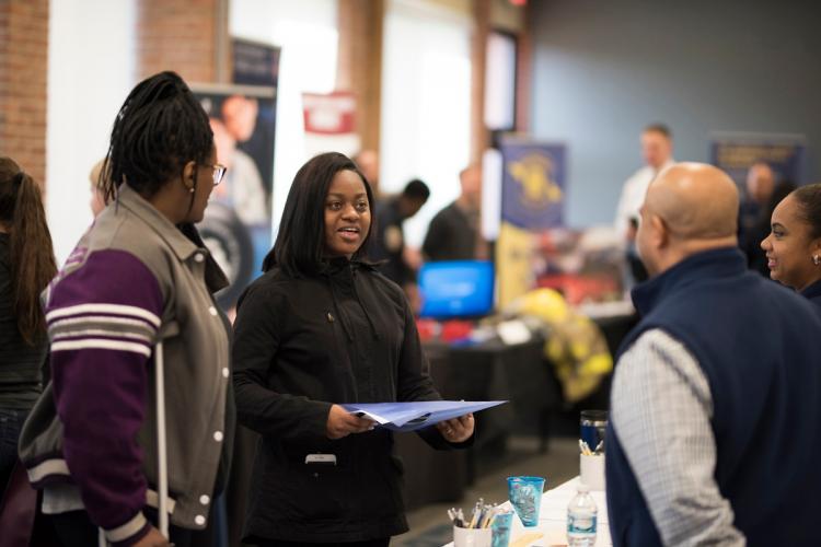 Two students talk to a potential employer at the Criminal Justice Job and Internship Fair.