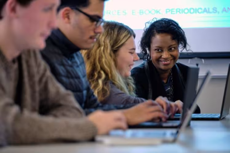 English professor Beverly Shannon working with students at a table.
