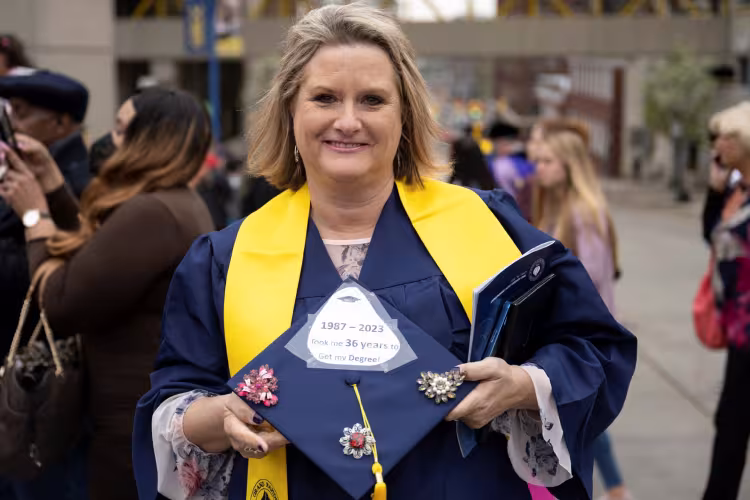 Pamela Syfert holding her mortarboard after commencement. 