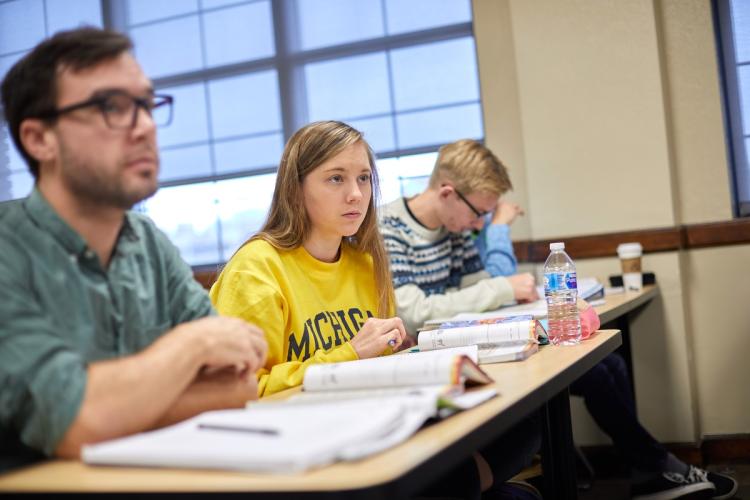 A student wearing a University of Michigan shirt in a classroom.