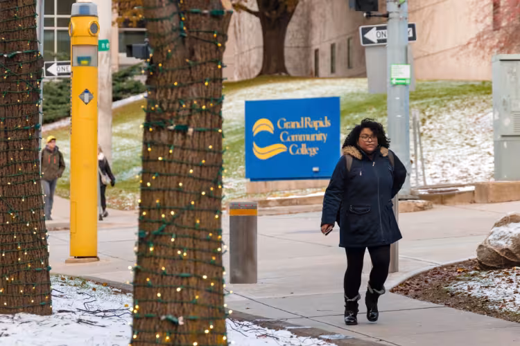 Student walking on campus near lighted trees. 
