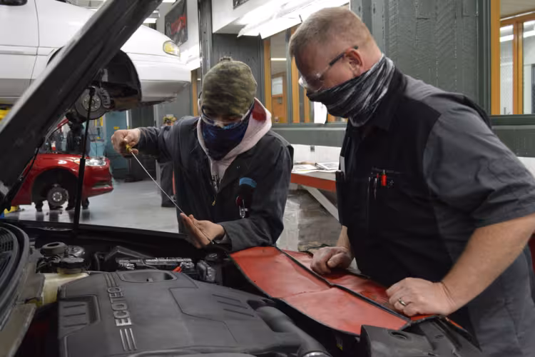 Isaac Bajema, a Grandville High School senior, checks oil while instructor Chris Yetzke looks on.