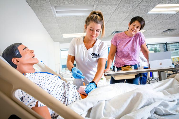 GRCC Nursing student working with an manikin simulator with a professor looking on.