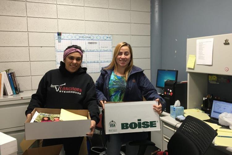 Two TRIO students hold up boxes of school supplies.