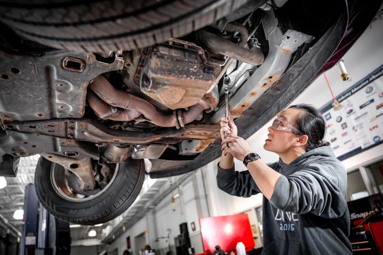 Student working under a car in a GRCC Automotive Tech class.