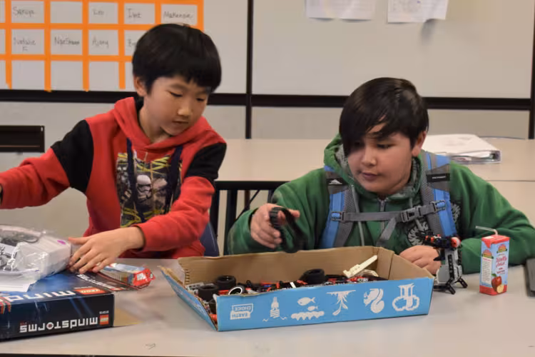 Kelloggsville Middle School students Cody Liang and Eman Marasigan look through a box of parts for their robot.