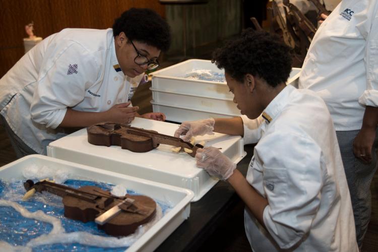 Students Kezia Stinson and Bryonna Farmer use chocolate to repair part of a violin.