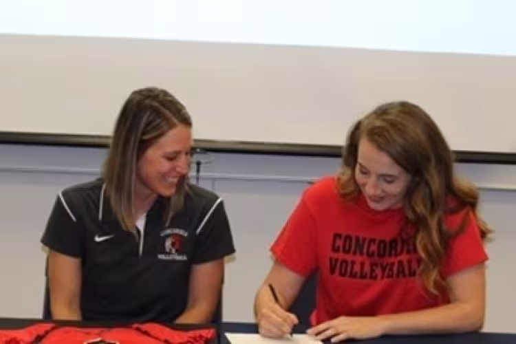 Lena Thompson signs a document as a Concordia University staffer watches.