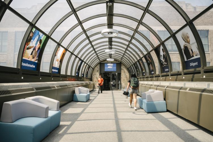 A two people walk through a sunny tunnel at GRCC