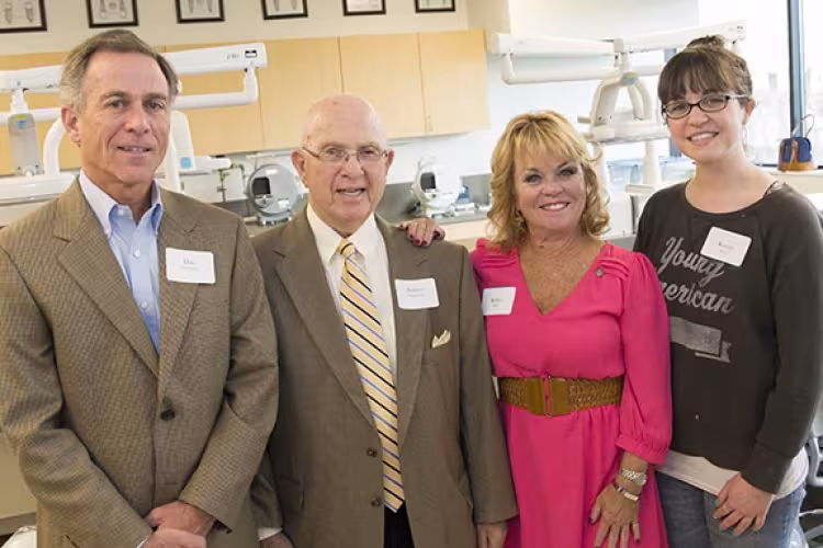 A group of four individuals standing in a dental lab.