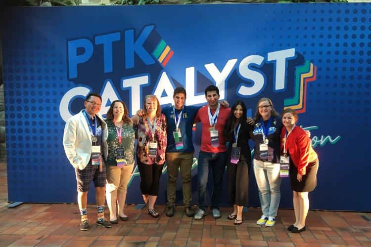 Members of Alpha Upsilon Kappa stand in front of a sign that says "PTK Catalyst."
