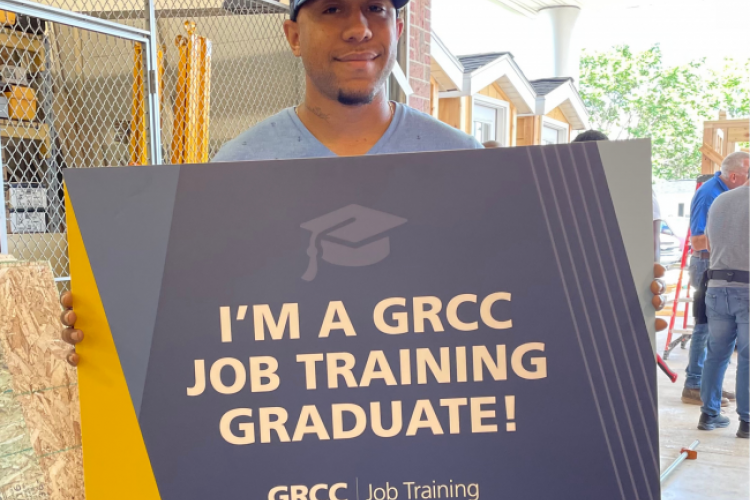 Tevon Bryant holding a sign reading "I'm a GRCC Job Training graduate!"