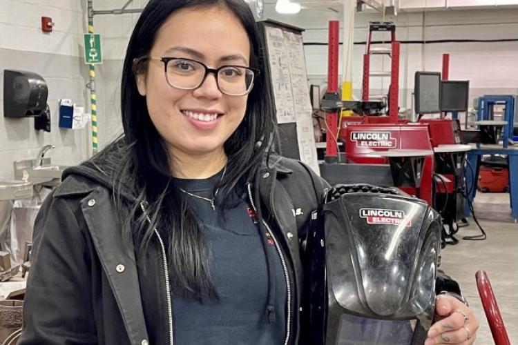 Stephany Borjas holding her welding helmet.
