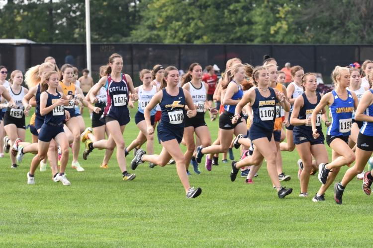 Women cross country team members racing in a large group.
