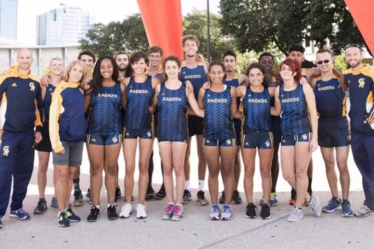 The coaches and members of the men's and women's cross country teams stand under the Calder.