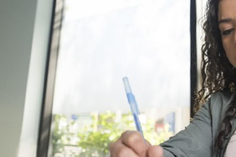 A student writes on a notepad. 