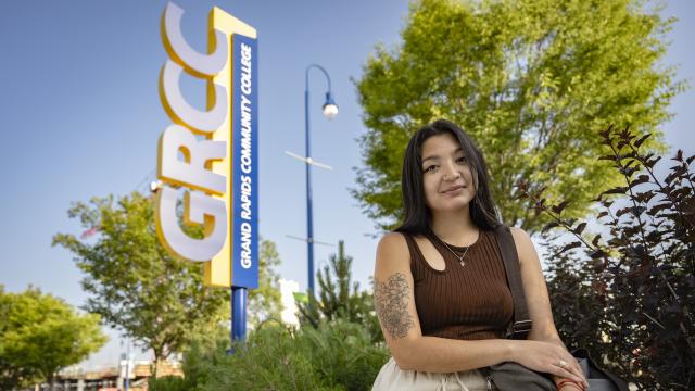Student sitting in front of a GRCC sign