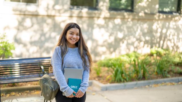A person standing outside at GRCC holding books