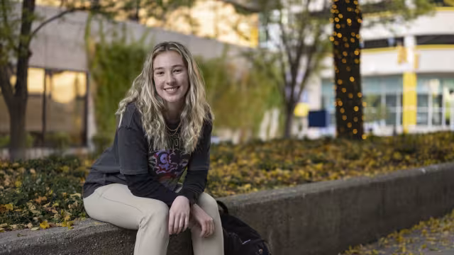 Student sitting outside on the commons in the fall